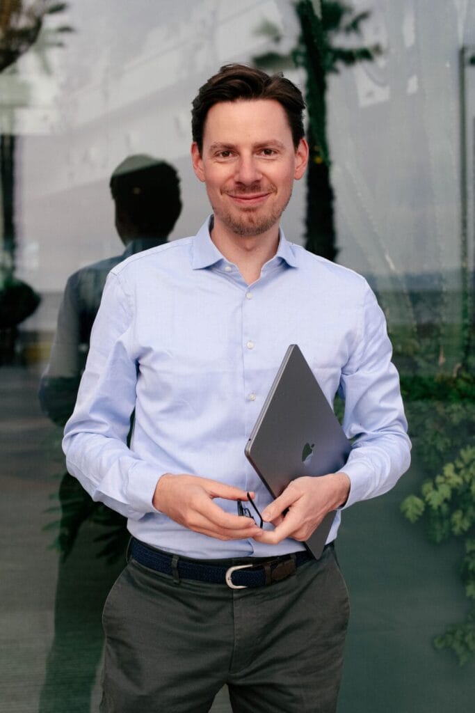 Mann mit Laptop vor Glaswand